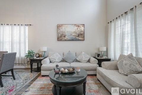 A living room with a grey couch, a coffee table, and a painting on the wall.