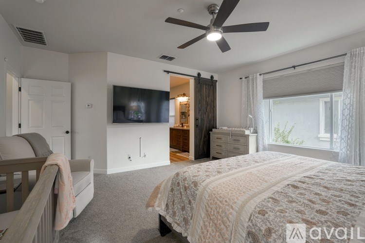 A bedroom with a large bed and a television on the wall.