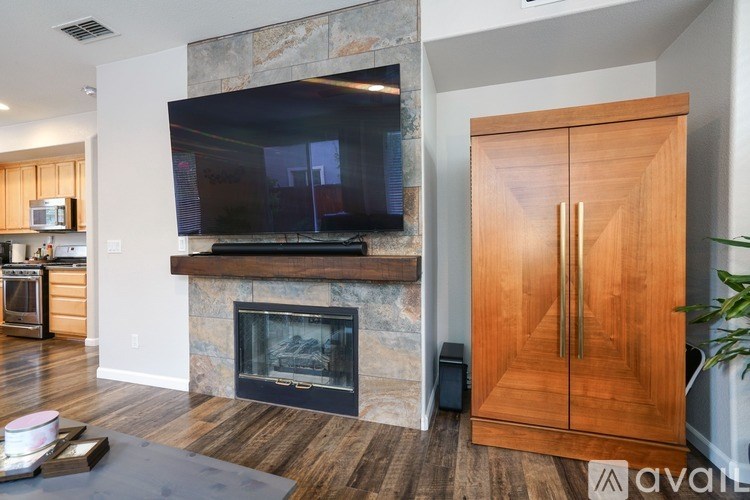 A modern kitchen with a stone fireplace and a flat screen TV mounted above it.