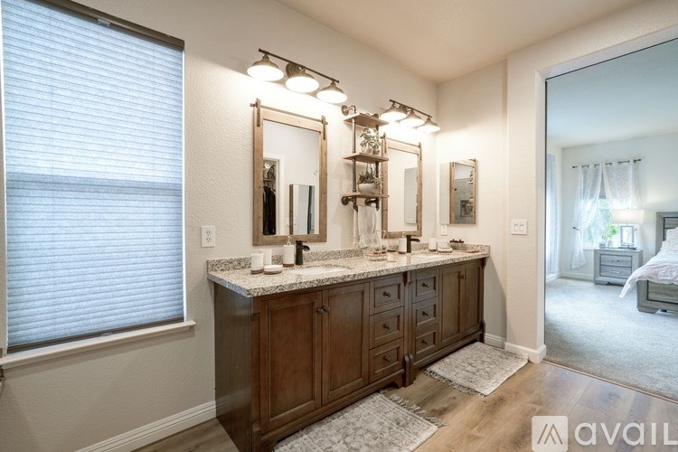 A bathroom with a vanity, mirrors, and a rug.