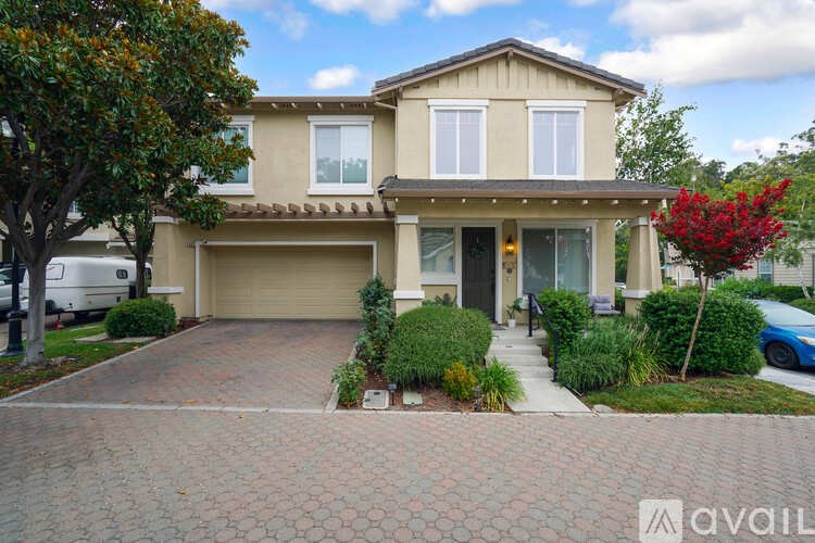 A house with a driveway and a tree in front of it.