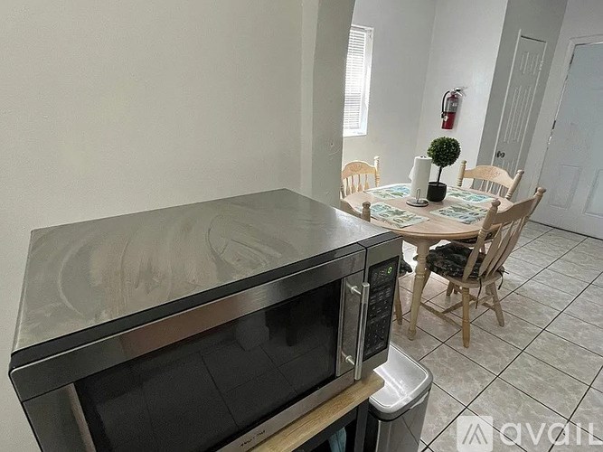 A kitchen with a microwave, oven, and a dining table with chairs.