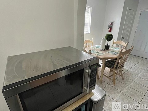 A kitchen with a microwave, oven, and a dining table with chairs.