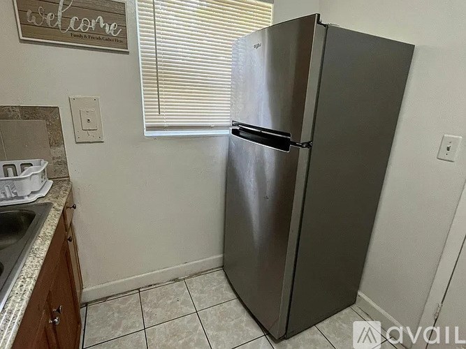 A stainless steel refrigerator stands in a kitchen corner.