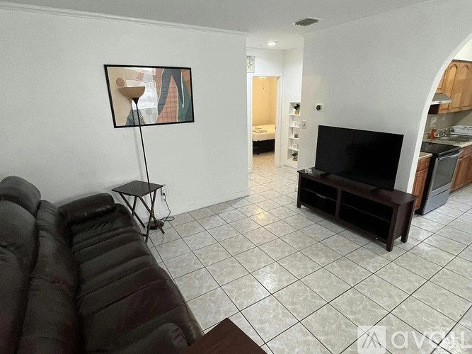 A living room with a black couch and a television.