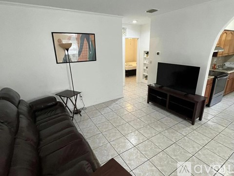 A living room with a black couch and a television.
