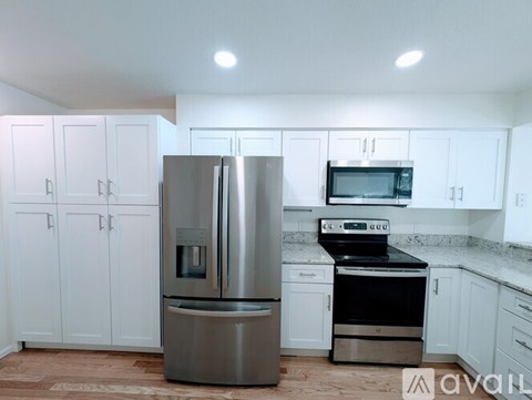 A kitchen with white cabinets and a stainless steel refrigerator.