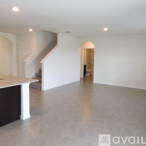 A spacious room with a staircase and a doorway leading to another room.