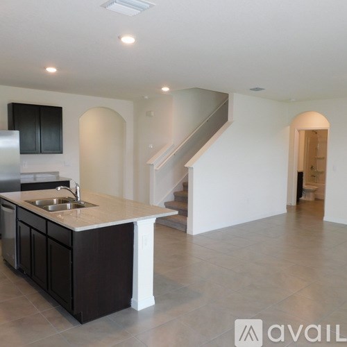 A kitchen with a sink and a stainless steel refrigerator.