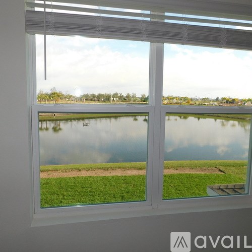 A window with a view of a lake and greenery outside.