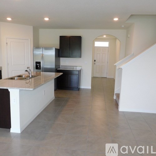 A kitchen with a refrigerator, sink, and cabinets.