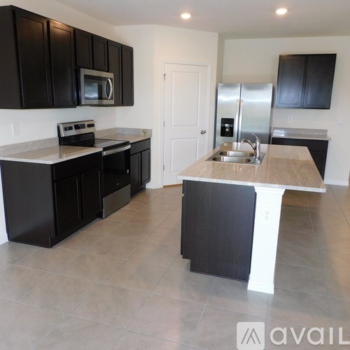 A kitchen with black cabinets and a white island.