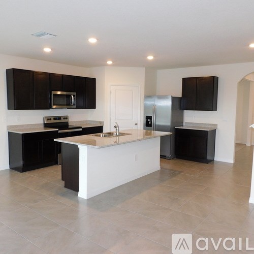 A kitchen with black cabinets and a white island.