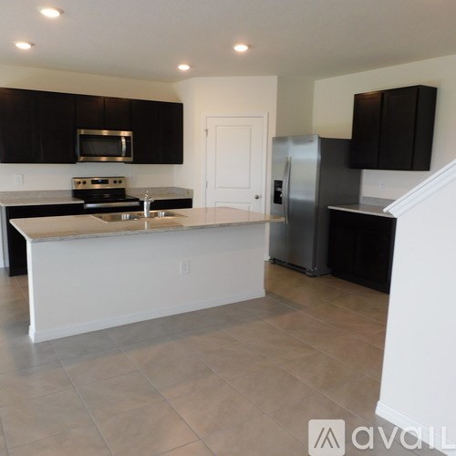 A kitchen with black cabinets and a white island.