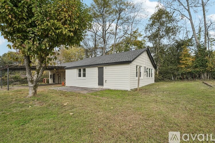 A house with a grey roof and white walls is surrounded by trees.