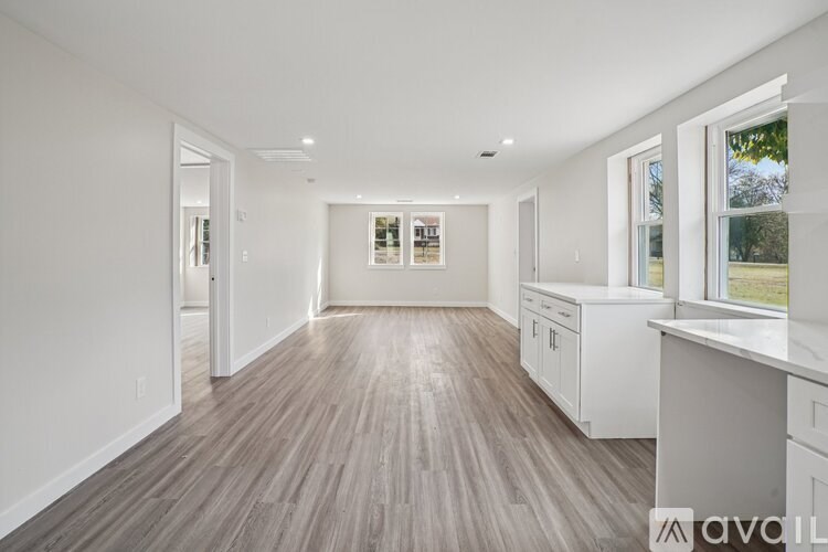 A spacious kitchen with white cabinets and a wooden floor.