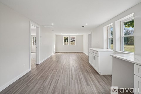 A spacious kitchen with white cabinets and a wooden floor.