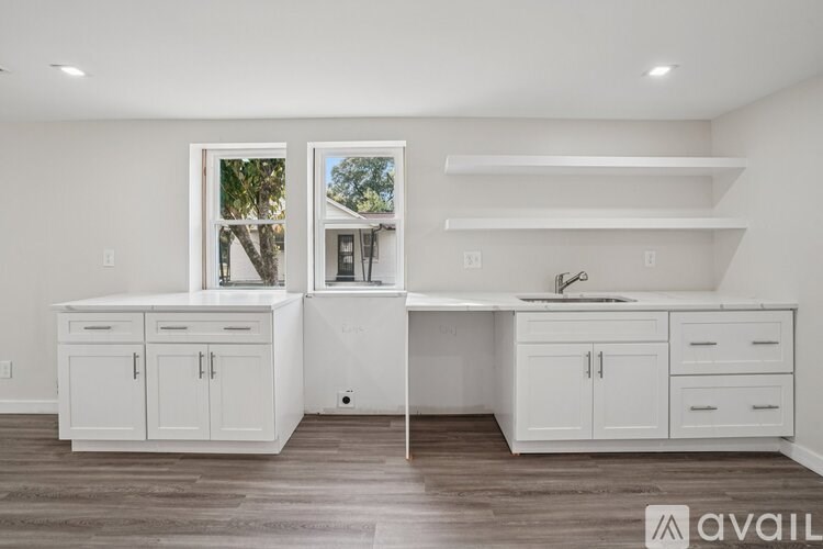A kitchen with white cabinets and a window overlooking a tree.
