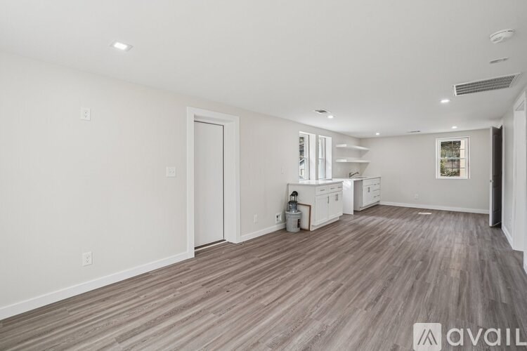 A spacious room with wooden flooring and white walls.