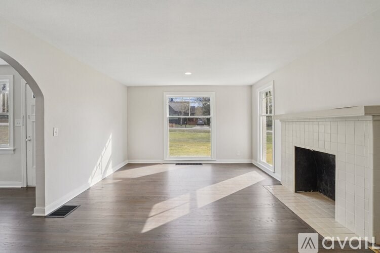 A spacious living room with a fireplace and a view of the backyard through the window.