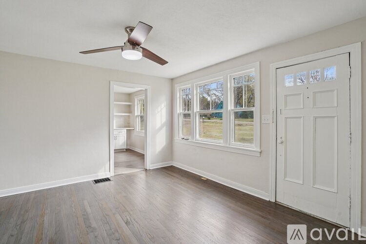 A room with a ceiling fan and a door leading to another room.