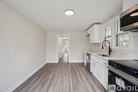 A kitchen with white cabinets and a wooden floor.
