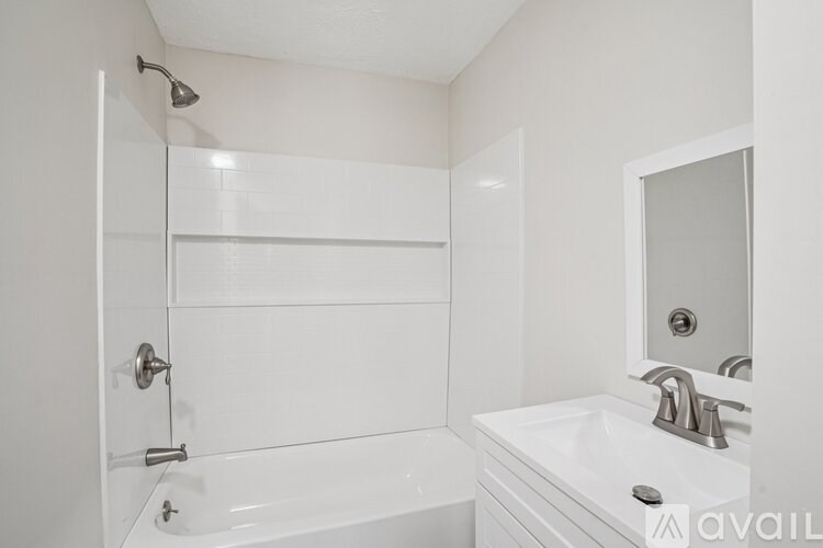 A white bathroom with a tub, sink, and mirror.