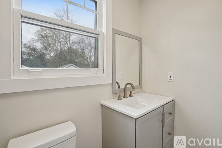 A bathroom with a toilet, sink, and window.