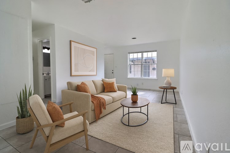 A living room with a beige couch, a chair, and a rug.