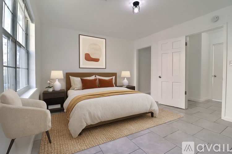 A bedroom with a large bed, a chair, and a painting on the wall.