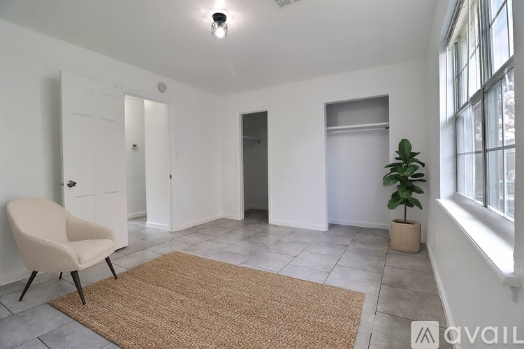 A room with a beige rug, a chair, and a plant.