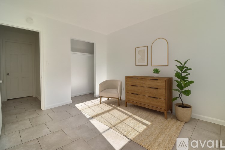 A room with a chair, a plant, and a dresser.