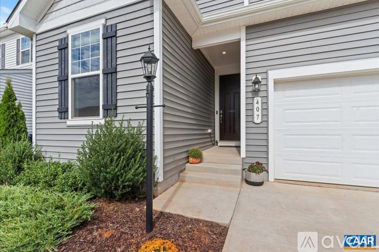 A grey house with a black lamp post in front.