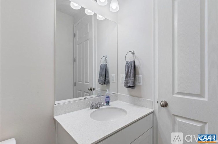 A white bathroom with a sink, mirror, and towel rack.