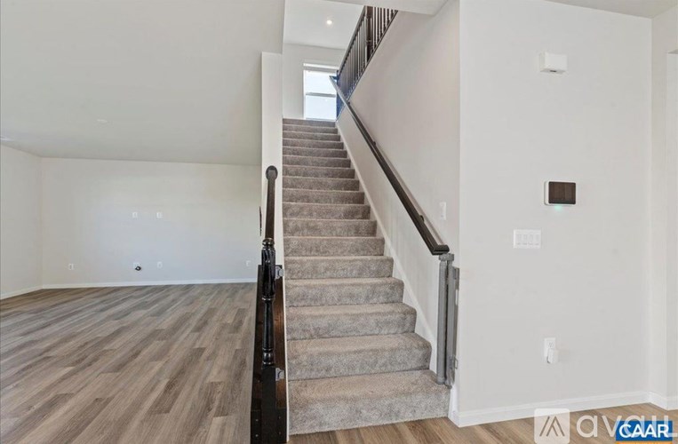 A staircase with a wooden handrail leads up to a window.
