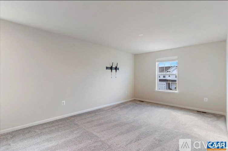 A sparsely furnished room with a window and a wall-mounted cross.