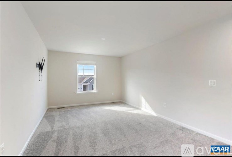 A room with a carpeted floor and a window showing a house.