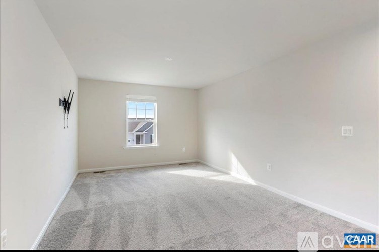 A spacious room with a carpeted floor and a window showing a building outside.