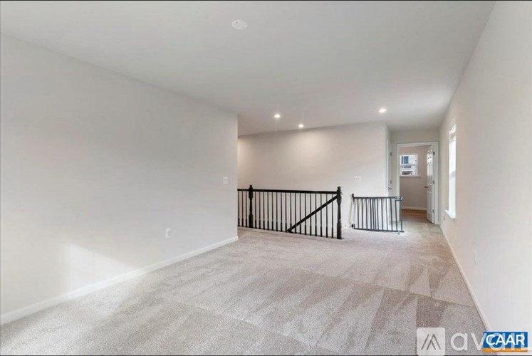 A spacious room with a carpeted floor and a black railing.