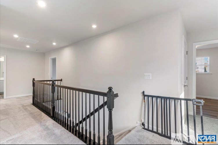 A room with a black railing and a carpeted floor.