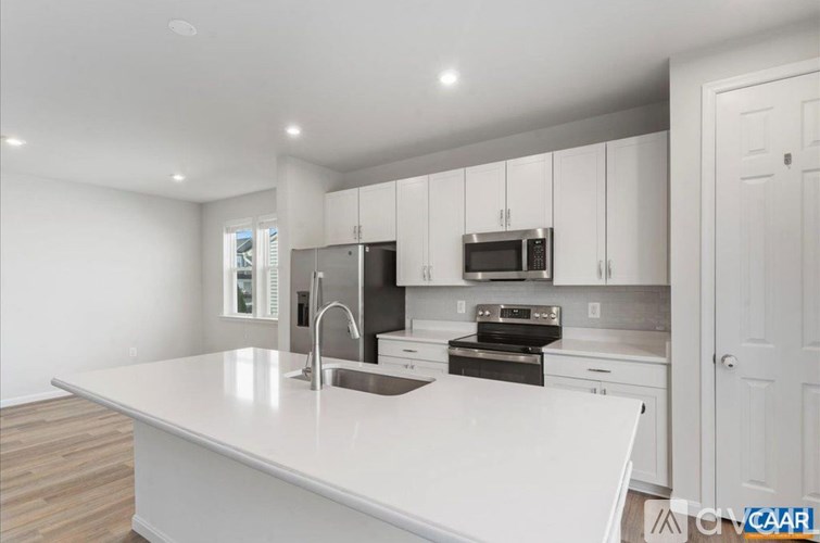 A white kitchen with a sink and stove top.