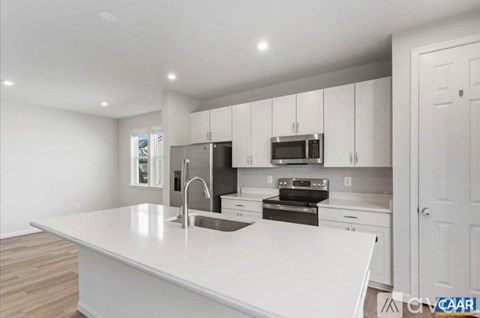 A white kitchen with a sink and stove top.