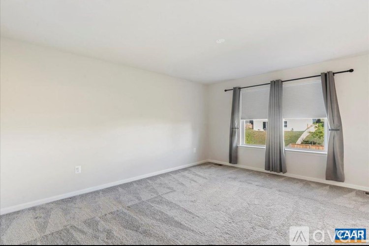 A room with a large window covered by grey curtains.