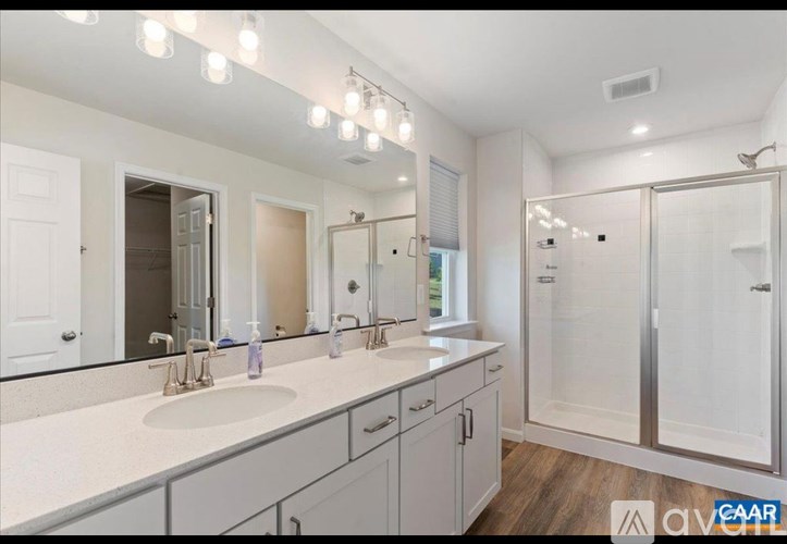 A bathroom with a double sink vanity and a walk-in shower.