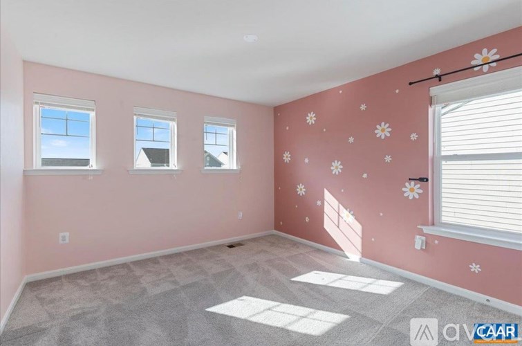 A room with pink walls and three windows.