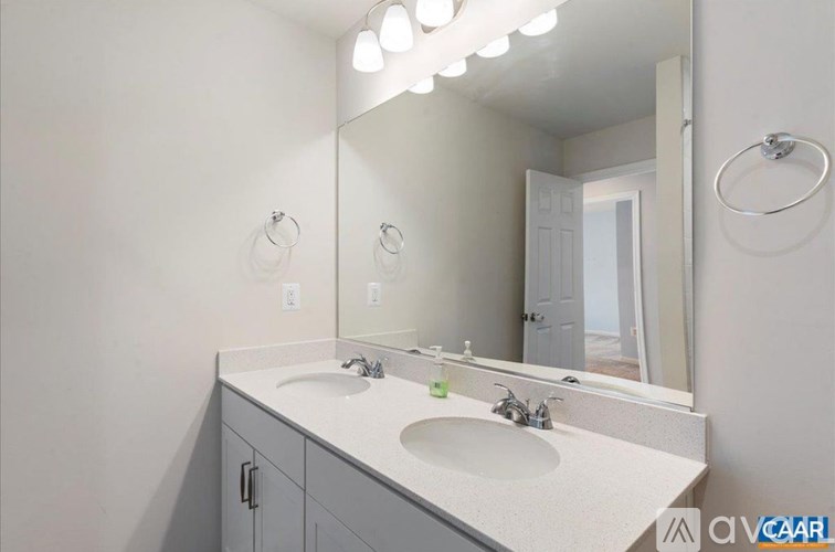 A bathroom with a double sink vanity and a large mirror above it.
