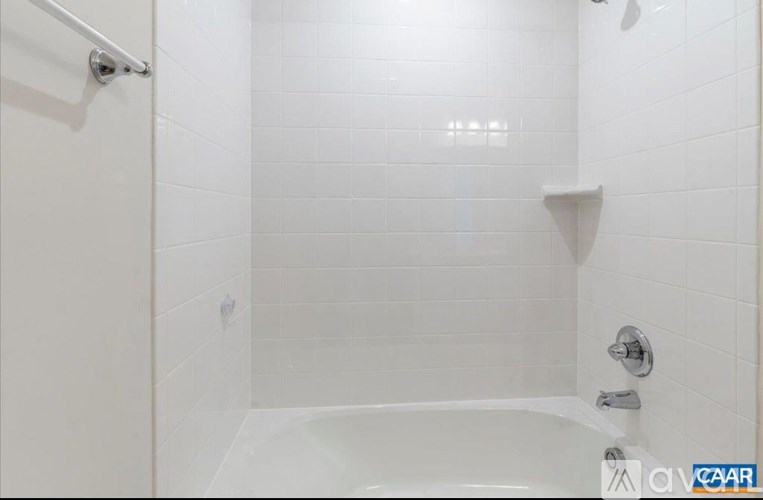 A white tiled bathroom with a white tub and shower.