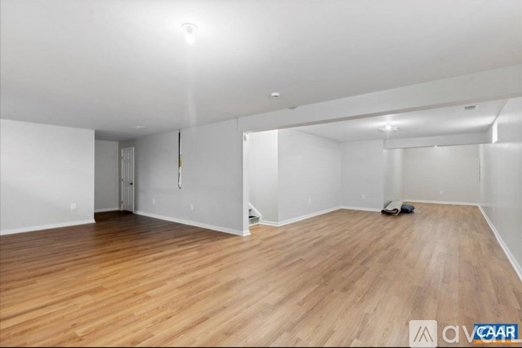 A room with wooden flooring and white walls.