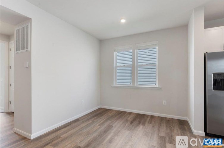 A room with wooden flooring and a window with white blinds.