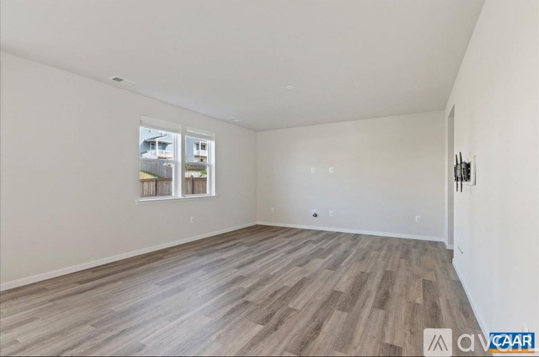 A room with wooden flooring and a window showing a view of a building.